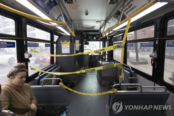 지난달 23일(현지시간) 코로나19 예방을 위해 운전석 주변에 차단선이 설치된 미국 뉴욕 시내버스 안에 한 여성이 탑승해 있다. [사진=AP/연합뉴스]