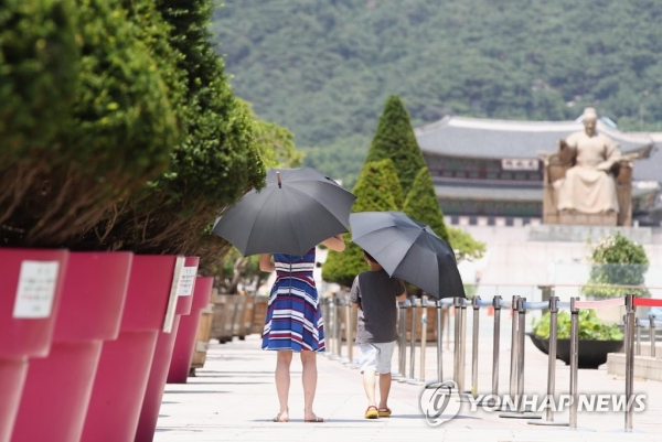 지난 14일 서울 광화문 광장을 찾은 한 가족이 우산을 쓰고 걷고 있다. [사진=연합뉴스]