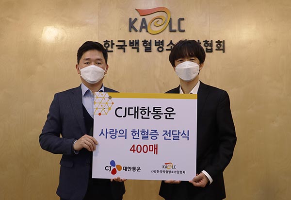 CJ대한통운 박진규 부장(왼쪽)이 한국백혈병소아암협회 서용화 과장(오른쪽)에게 헌혈증을 전달하고 기념촬영 하고 있다. [사진=CJ대한통운]