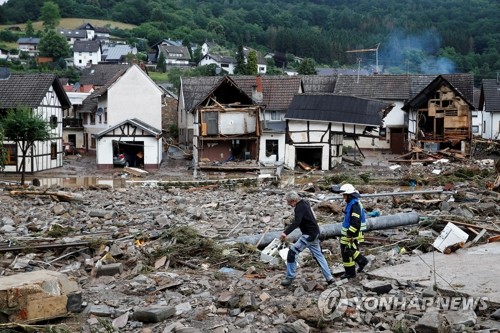 독일 서부 슐트에서 15일(현지시간) 폭우와 홍수가 휩쓸고 간 주택가의 잔해 사이를 소방관과 주민이 걸어가고 있다. [로이터=연합뉴스]