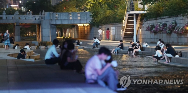 서울 낮 기온이 35도를 넘으며 올여름 최고기온을 기록한 22일 밤 시민들이 청계천에서 더위를 식히고 있다. [사진=연합뉴스]