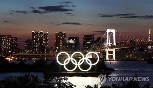 도쿄올림픽 개막을 하루 앞둔 22일 밤 일본 도쿄 스카이라인을 배경으로 오륜 조형물이 환하게 불을 밝히고 있다. [연합뉴스]