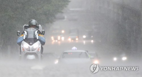 서울 지역에 강한 소나기가 내린 19일 오후 서울 중구 서소문로에서 택배기사가 비가 쏟아지는 도로를 지나고 있다. [연합뉴스]