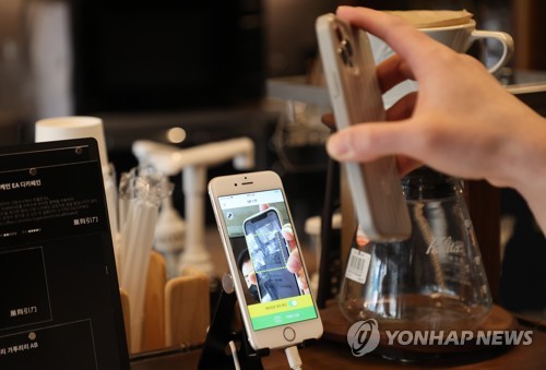 서울 시내 카페에서 방문 고객이 전자출입명부 QR코드를 태그하는 모습. [연합뉴스]