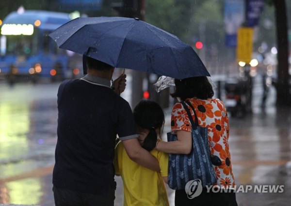 서울 보신각 인근 거리에서 한 가족이 우산 하나를 쓴 채 걸어가고 있다. [사진=연합뉴스]