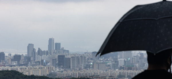 8일 오후 서울 남산 전망대에서 한 시민이 우산을 쓰고 서울 용산과 강남 일대를 바라보고 있다. [사진=연합뉴스]