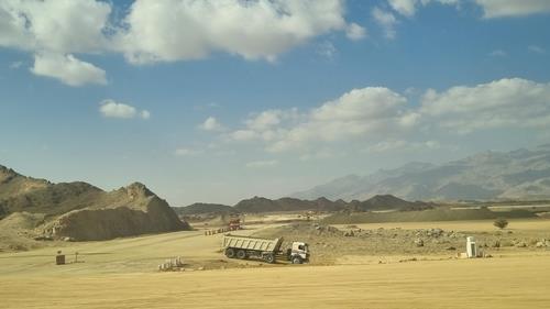 사우디아라비아 북서부 네옴시티로 향하는 도로변을 덤프트럭이 오가고 있다. [연합뉴스]