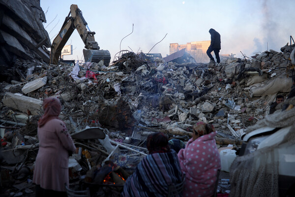 튀르키예 지진으로 무너진 건물 잔해 위에서 시민들이 혹시 있을 지도 모를 생존자를 찾고 있다. [로이터=연합뉴스]