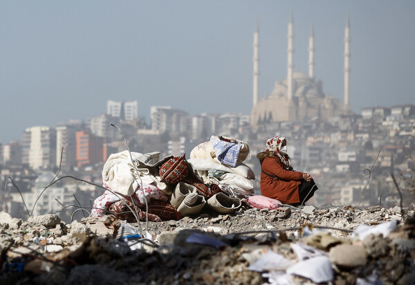 강진 발생 9일째인 14일(현지시간) 튀르키예 카흐라만마라슈에서 한 여성이 지진으로 붕괴해 폐허가 된 집터에 앉아 있다. [로이터=연합뉴스]