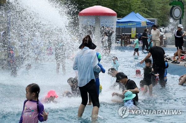 지난 27일 광주 북구 시민의숲 물놀이장에서 시민들이 아이들과 함께 떨어지는 물줄기 아래에 있다. [사진=연합뉴스]