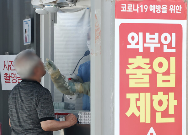 코로나 하루 확진자가 치솟으면서 재유행 우려가 나오는 31일 서울의 한 보건소 선별진료소에서 시민이 코로나19 검사를 받고 있다. [연합뉴스]