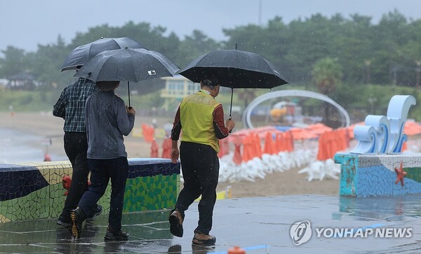 비가 쏟아진 지난달 30일 오전 제주시 이호해수욕장에서 우산을 든 이들이 산책하고 있다. [사진=연합뉴스]