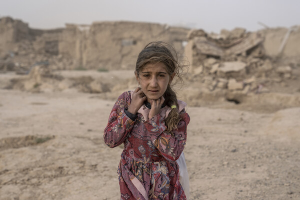 지난 12일 아프가니스탄 서부 헤라트주 젠다잔 지역에서 지진이 발생한 후 한 아프가니스탄 소녀가 모래폭풍 속에 구호품을 들고 가고 있다. [AP=연합뉴스]