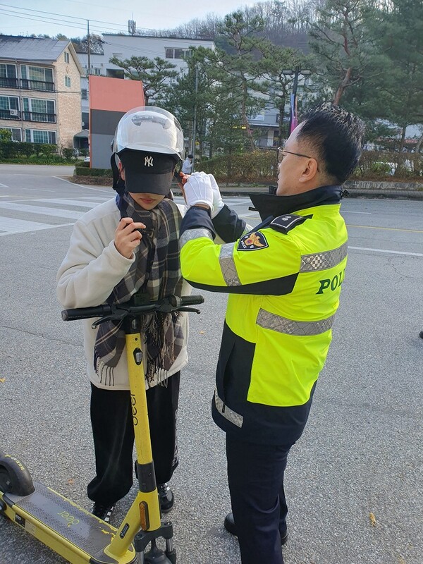 캠페인에 참여한 이천경찰서 관계자가 전동킥보드 이용 학생에게 헬멧을 씌워주고 있다. [청강대 제공]