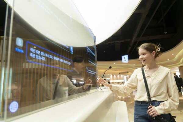 에비뉴엘 잠실점 1층과 롯데월드몰 지하 1층 안내데스크에 설치된 ‘트랜스 토커’를 외국인 모델이 활용하고 있는 모습. [SK텔레콤 제공=뉴스퀘스트]