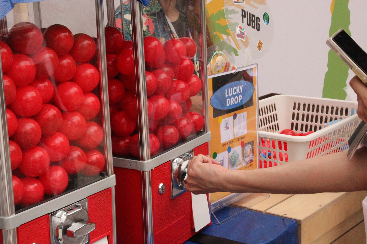 팝업스토어 '퇴장' 전에 위치한 '체크인 존'. 스탬프 4개 이상을 찍은 '여권'을 스토어 관계자에 보여주면 '럭키 드롭'에 도전할 수 있다. '럭키 드롭'에는 다양한 상품들이 무작위로 섞여 있다. 한 관람객이 '럭키 드롭'을 뽑고 있다. [사진=김민우 기자]