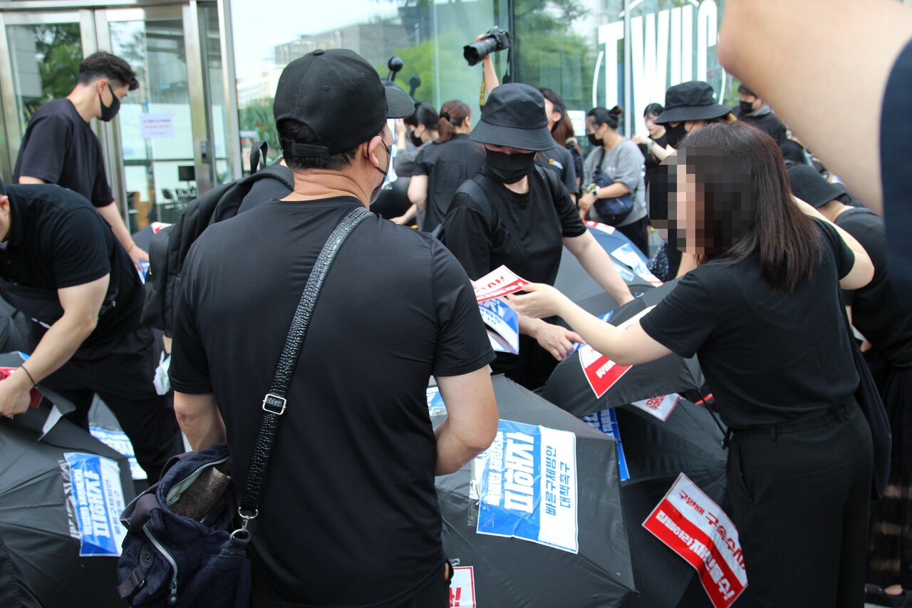 13일 서울 강남 구티몬사옥에서 열린 '검은우산' 집회에서 티메프 피해자들이 우산에 경영진 규탄 문구 스티커를 붙이고 있다. [사진=김민우]