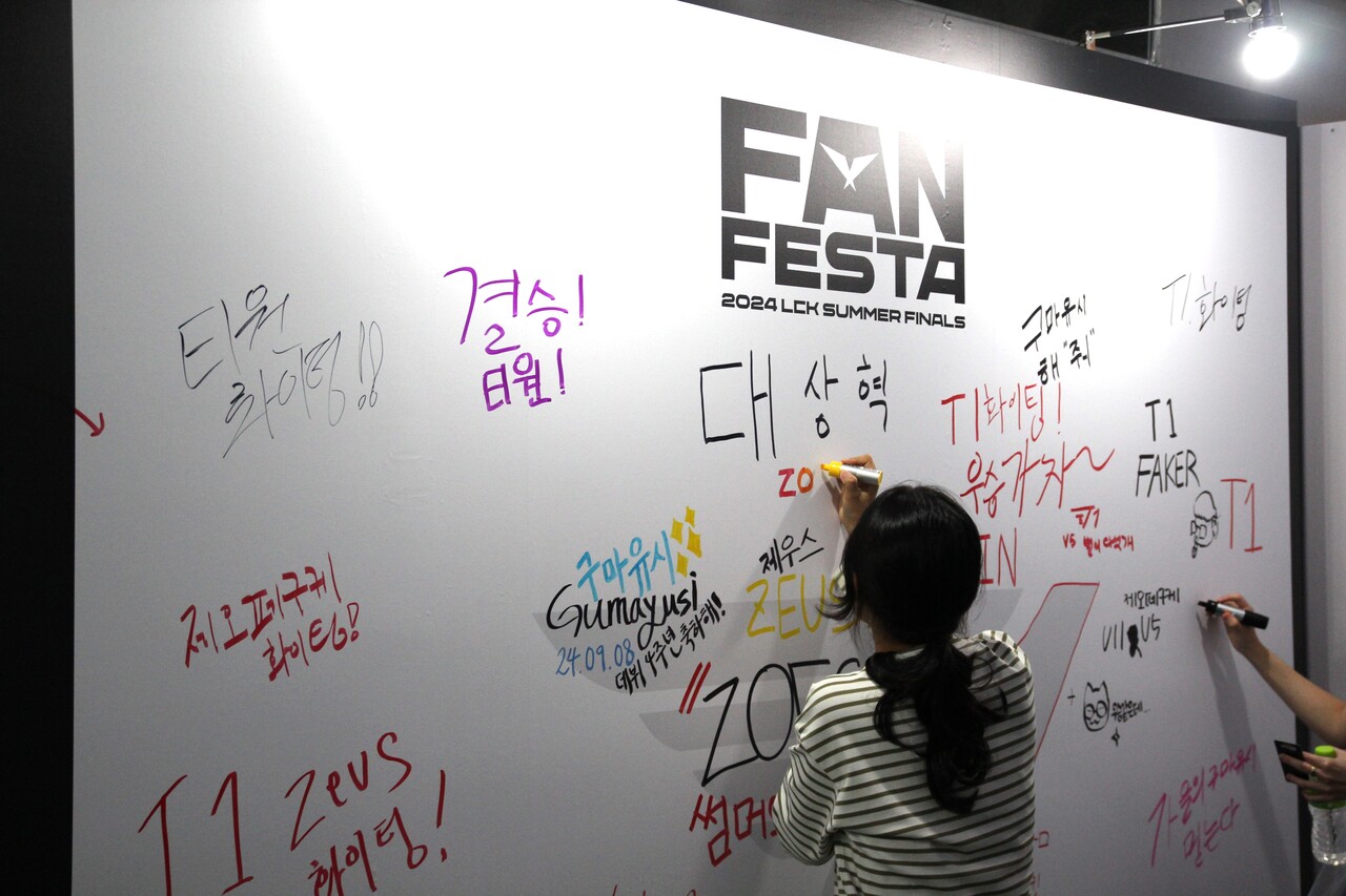 6일 팬 페스타에 방문한 한 관람객이 벽 부스에 응원 메시지를 남기고 있다. [사진=김민우 기자]