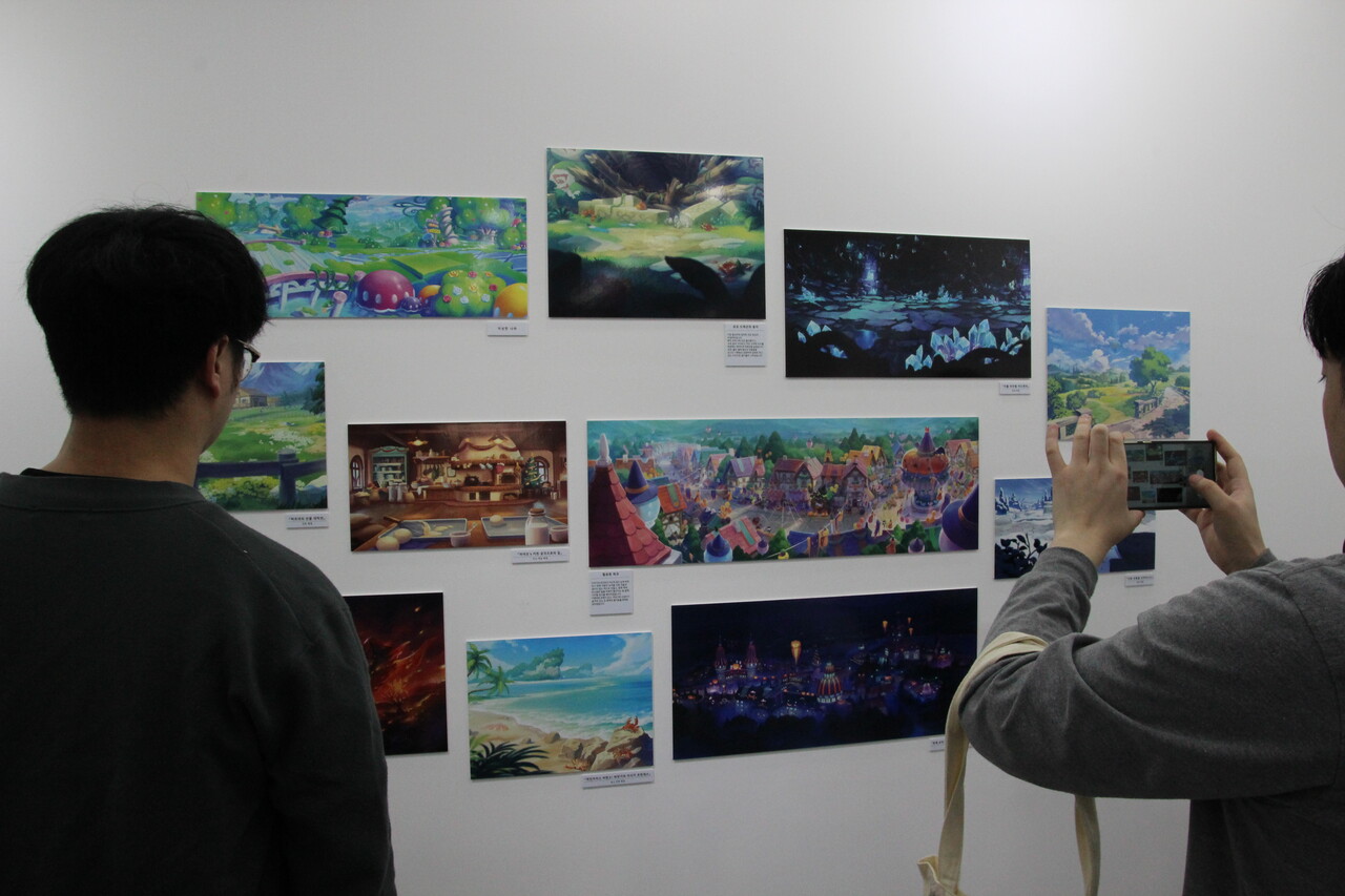 현장을 찾은 유저들이 전시회에서 첫 공개된 미공개 일러스트를 눈으로 관람하고 사진을 찍고 있다. [사진=김민우 기자]