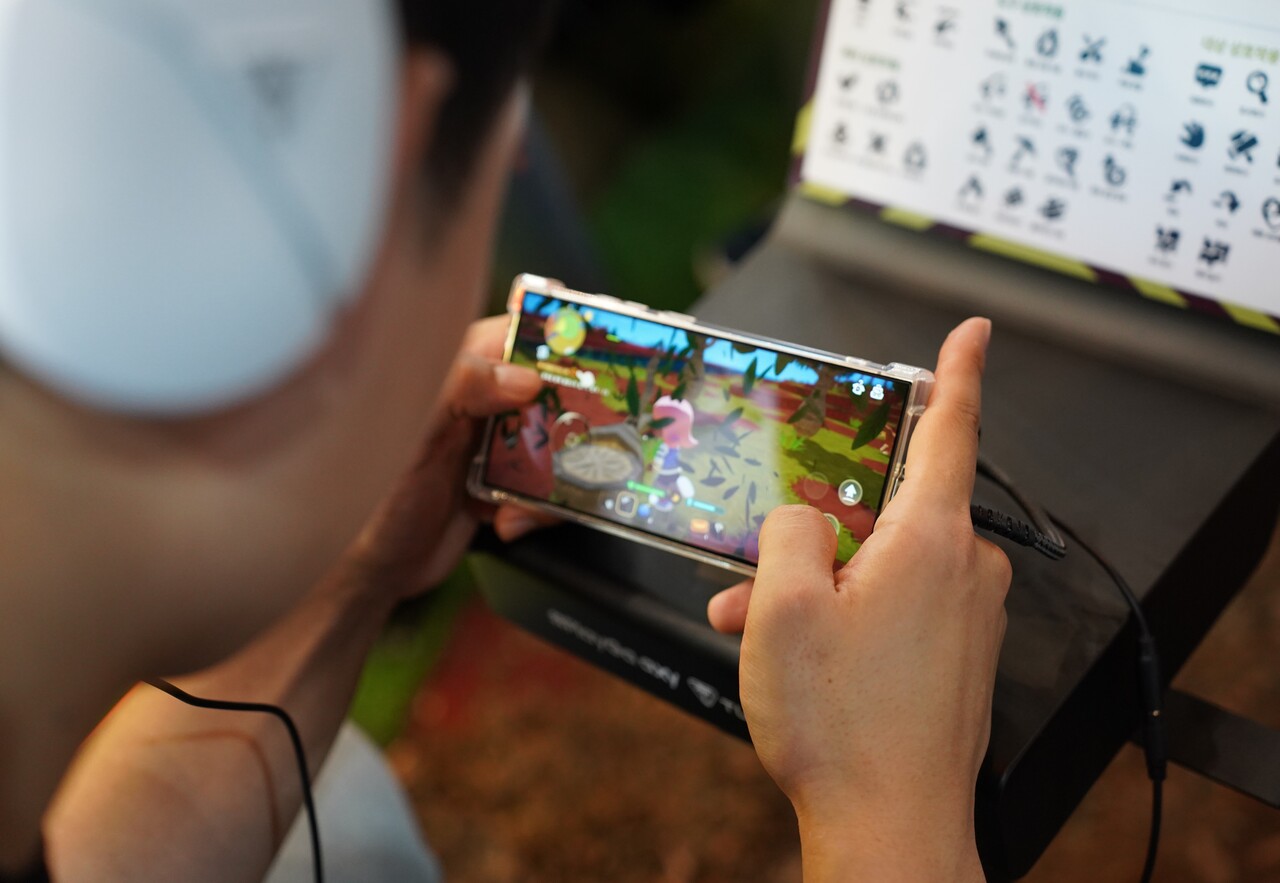 크래프톤 '딩컴 투게더' 부스에서 유저가 스마트폰을 게임을 즐기고 있다. [사진=김민우 기자]