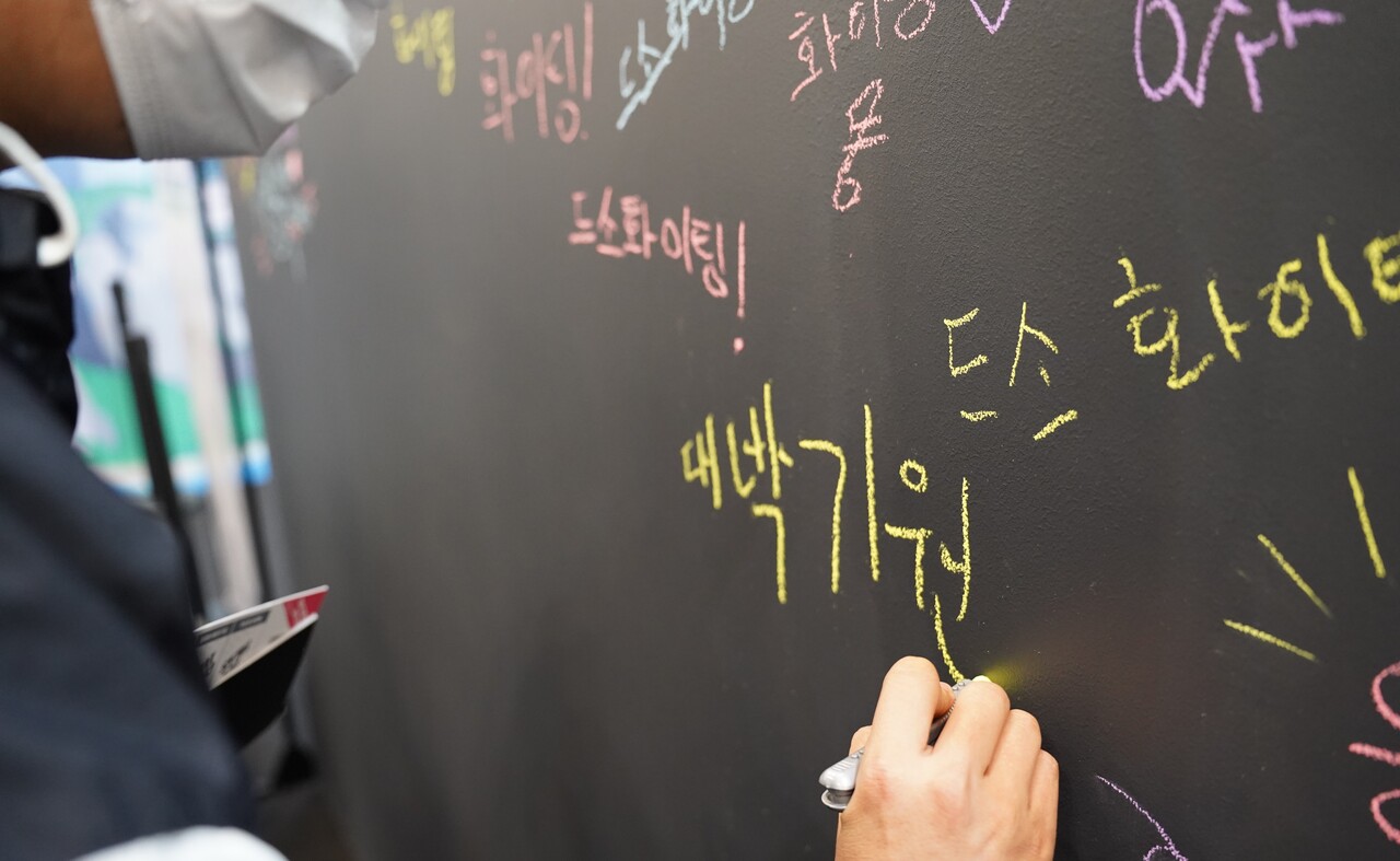 웹젠 '드래곤소드'를 관람객이 응원보드에 '대박기원'을 쓰고 있다. [사진=김민우 기자]