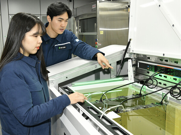 액침냉각설비에 담긴 냉각유와 서버를 테스트하고 있는 HD현대오일뱅크 직원들 [HD현대오일뱅크 제공=뉴스퀘스트]