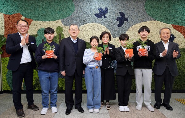 김신연 한화 사장(왼쪽 세번째)이 진잠초 학생들과 함께 공기정화를 위해 한화가 벽면에 조성한 모스월 앞에서 반려 식물을 들고 있다. [사진=한화]