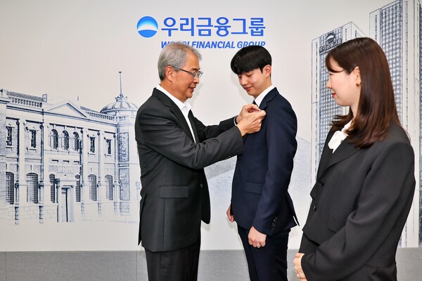 우리금융그룹 임종룡 회장(왼쪽)이 그룹의 새 가족이 된 동양생명·ABL생명 직원에게 디지털 선도의 의미가 담긴 새로운 그룹 보조휘장을 달아주고 있다. [사진=우리금융그룹]