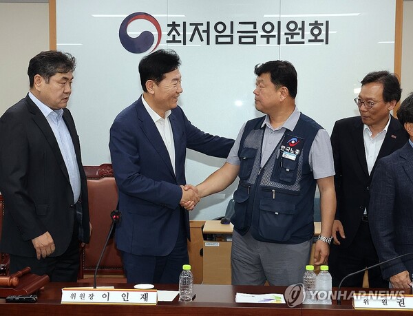 최저임금위원회 사용자위원 운영위원인 류기정 한국경영자총협회 전무(왼쪽 두 번째)와 근로자위원 운영위원인 류기섭 한국노총 사무총장(오른쪽 두 번째)이 10일 정부세종청사에서 열린 제12차 전원회의에서 내년 최저임금을 시간당 1만320원으로 17년만에 합의로 결정한 뒤 악수하고 있다. 왼쪽은 이인재 위원장. [사진=연합뉴스]