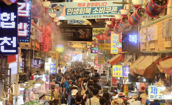 한국신용데이터(KCD)에 따르면 민생회복 소비쿠폰 배포가 시작된 첫째 주(7월 21~27일) 전국 소상공인 평균 카드 매출액은 전 주보다 2.2% 증가한 것으로 분석됐다. 부산 부산진구 부전시장에 상인회에서 내건 '민생회복 소비쿠폰 환영' 펼침막과 쿨링 포그가 방문객들을 맞이하고 있다. [사진=연합뉴스]