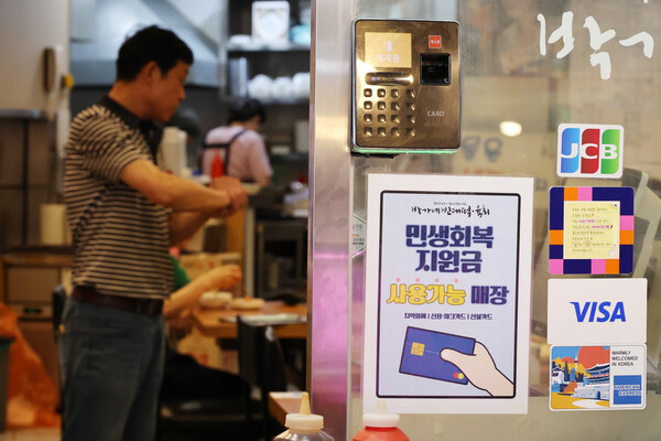 신한카드는 민생회복 소비쿠폰으로 영세 중소가맹점의 매출 증가와 함께 가맹점주의 개인 소비가 늘어나는 효과를 확인했다고 18일 밝혔다. 서울 시내의 한 가게에 붙은 민생회복 소비쿠폰 사용처 안내문. [사진=신한카드]